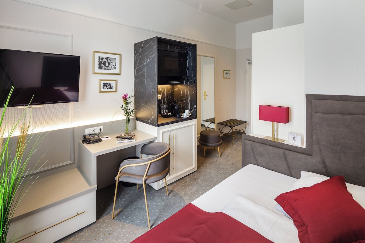 Une chambre d’hôtel équipée d’un lit, d’un bureau, d’une télévision, d’une kitchenette et d’un coin repas.