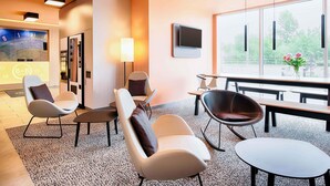 A modern hotel lobby with seating, a reception desk, and a large window offering a view of the outdoors. - B&B Hotel Rostock-Hafen (Rostock)