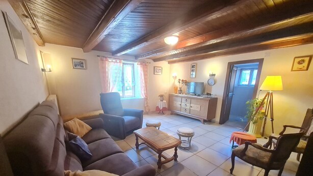 A living room with a sofa, armchair, coffee table, and a TV on a cabinet. - Charming Renovated Farmhouse, Terrace, Garden, Near Lakes & Nature, Close to Baccarat & Badonviller (Reherrey)