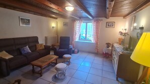 A living room with a sofa, armchair, ottoman, and a small table. - Charming Renovated Farmhouse, Terrace, Garden, Near Lakes & Nature, Close to Baccarat & Badonviller (Reherrey)