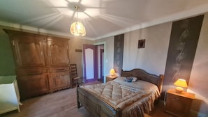 A bedroom with a wooden bed, two bedside lamps, a wardrobe, and a ceiling light fixture. - Charming Renovated Farmhouse, Terrace, Garden, Near Lakes & Nature, Close to Baccarat & Badonviller (Reherrey)