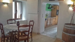 A dining area with a table set for four, wooden chairs, a vase, and a window with curtains. - Charming Renovated Farmhouse, Terrace, Garden, Near Lakes & Nature, Close to Baccarat & Badonviller (Reherrey)