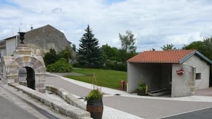 A small stone building with a tiled roof, a paved area, and a potted plant. - Charming 19th Century House in Mirabelle Country with Terrace and BBQ (Rozelieures)