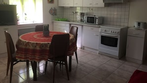 A kitchen with white cabinets, a microwave, an oven, and a dining table with chairs. - Charming 19th Century House in Mirabelle Country with Terrace and BBQ (Rozelieures)