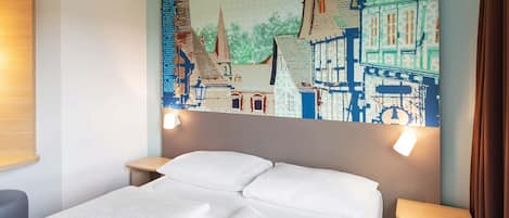 Habitación de hotel con una cama, dos mesitas de noche y un gran mural en la pared que muestra un paisaje urbano.