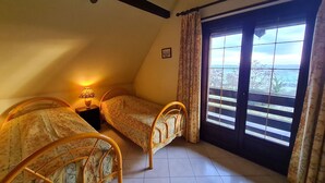 Une chambre avec deux lits, une fenêtre donnant sur un beau paysage et un ventilateur de plafond.