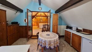 Une cuisine de taille réduite avec une table à manger, des placards en bois et une horloge bien visible.