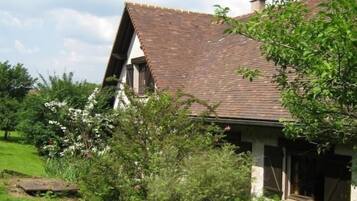 Traditional house surrounded by lush greenery and a well-maintained lawn.