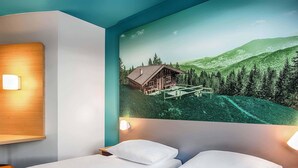Habitación de hotel con dos camas, un mural de una cabaña en la montaña y un cabecero de madera.