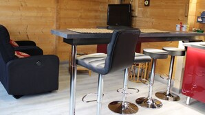 Un intérieur chaleureux de chalet en bois, avec un coin bar, des sièges et un téléviseur.