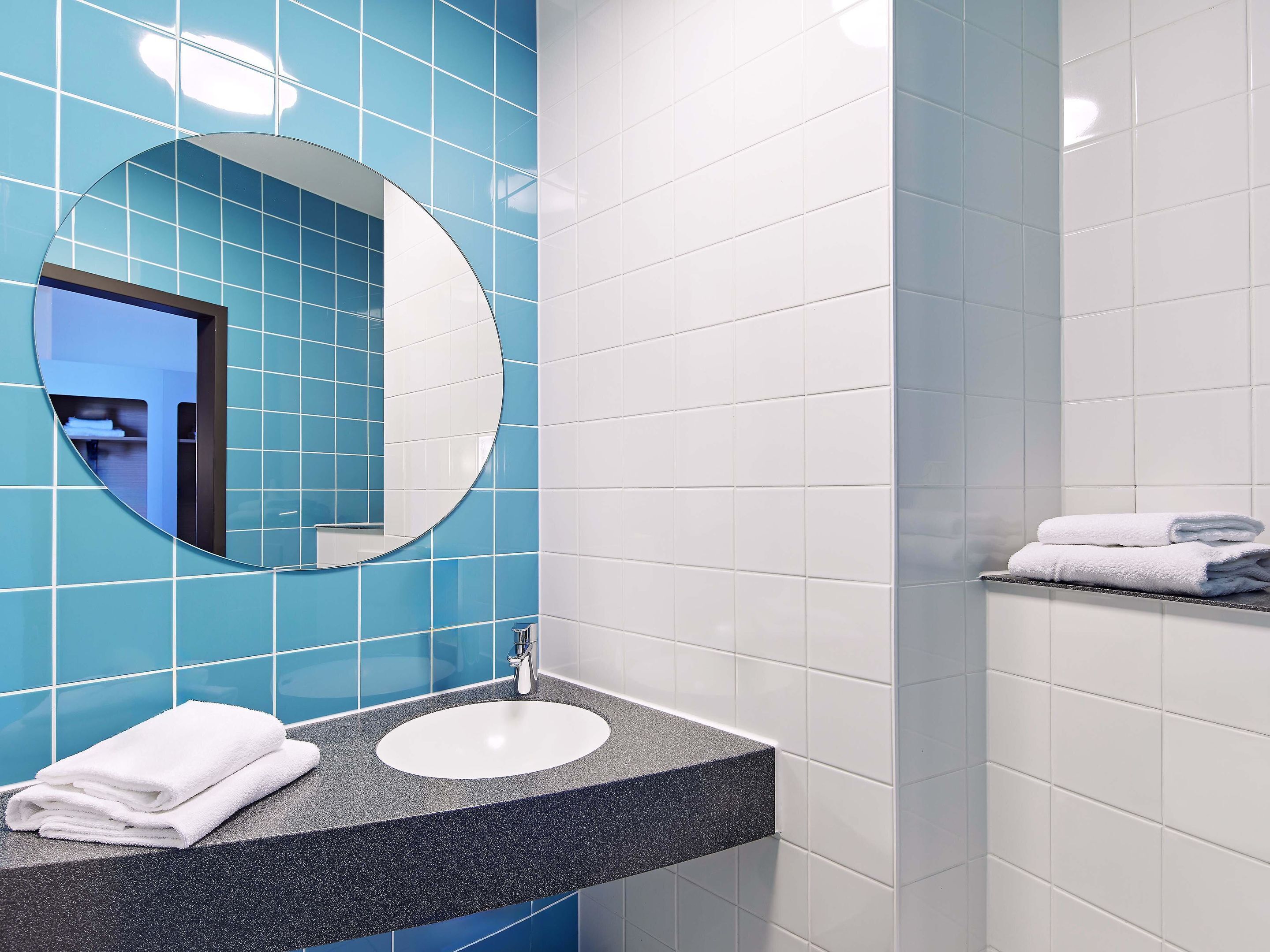 Un baño con lavabo, espejo y barra para toallas.
