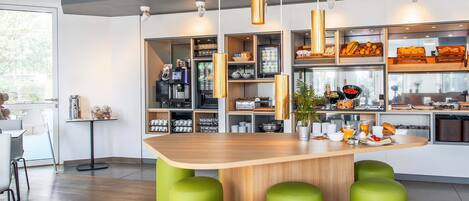 A modern kitchen with a central island, green stools, and various kitchen appliances.