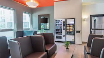 A modern waiting area with leather seating, a vending machine, and a flat-screen TV mounted on the wall.