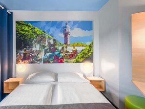 A bedroom with a large bed, two bedside tables, and a wall-mounted painting of a coastal scene. - B&B Hotel Neu-Ulm (Neu-Ulm)