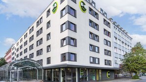 Un hôtel-boutique moderne avec une façade en verre, de nombreux étages et une vue dégagée sur le ciel.