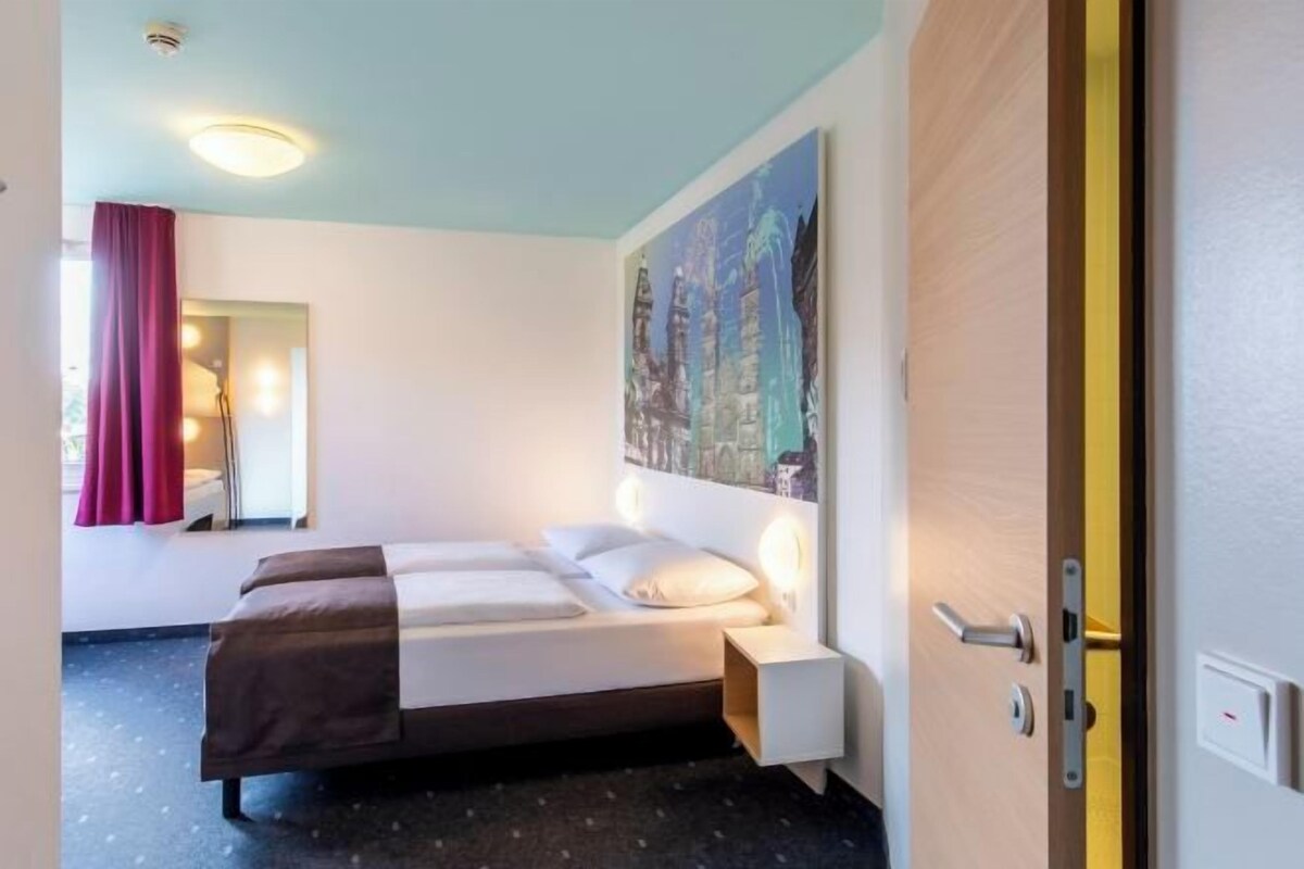 Ein Hotelzimmer mit Bett, Nachttisch und einem Bild an der Wand.