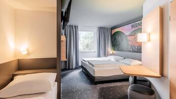 A hotel room with two beds, a desk, a chair, a TV, and a large window.