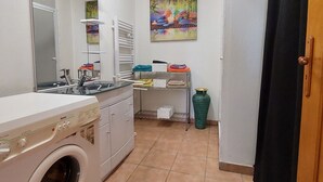 Pieni, käytännöllinen keittiö, jossa on pyykinpesukone, pesuallas ja pyykkiteline.