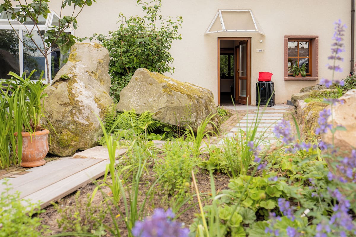 A garden pathway leading to a building with a door and windows.