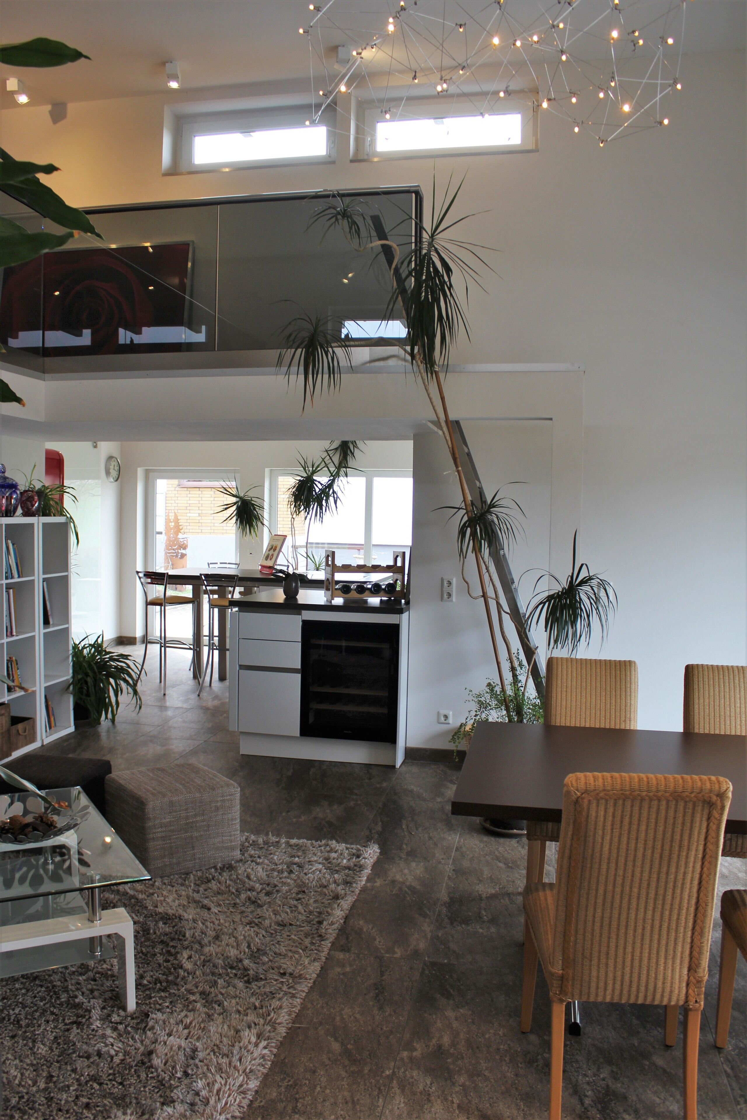 A modern kitchen with a dining area, featuring a large window, a dining table with chairs, and a kitchen island.