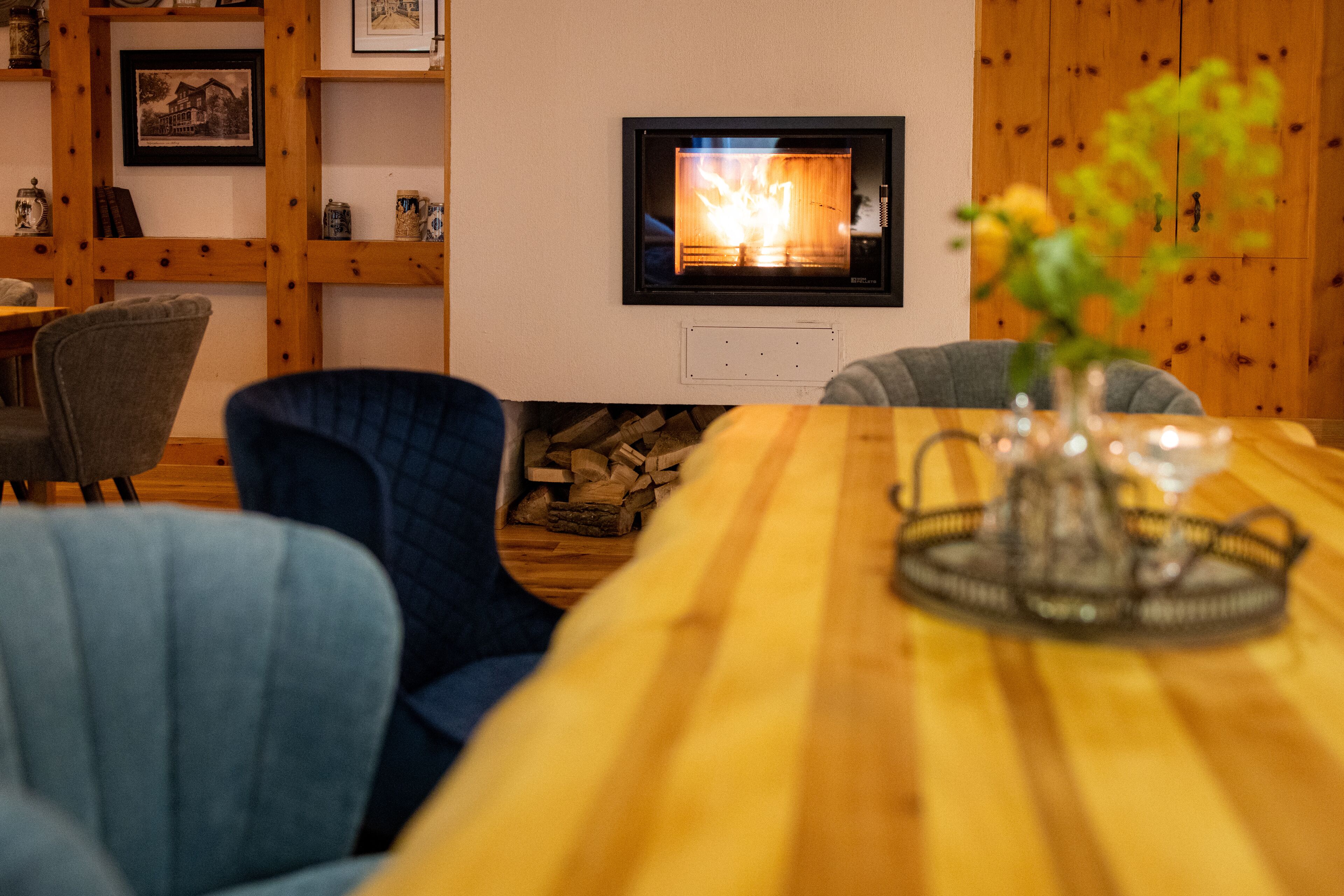 A cozy living room with a fireplace, wooden furniture, and a vase with flowers on the table.