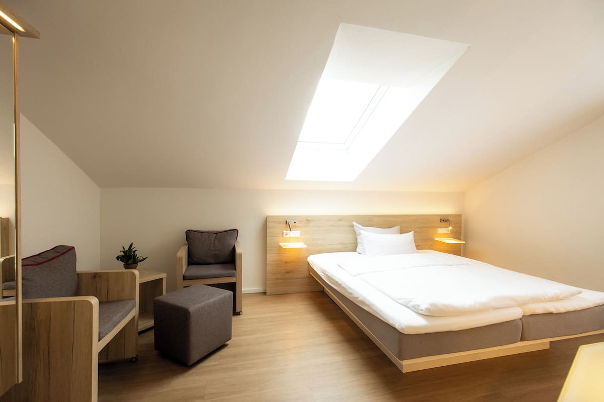 A modern bedroom with a skylight, a bed, a desk, and a chair.