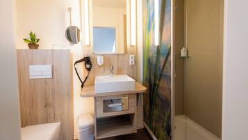 A modern bathroom with a wooden vanity, a white sink, a mirror, and a shower enclosure.