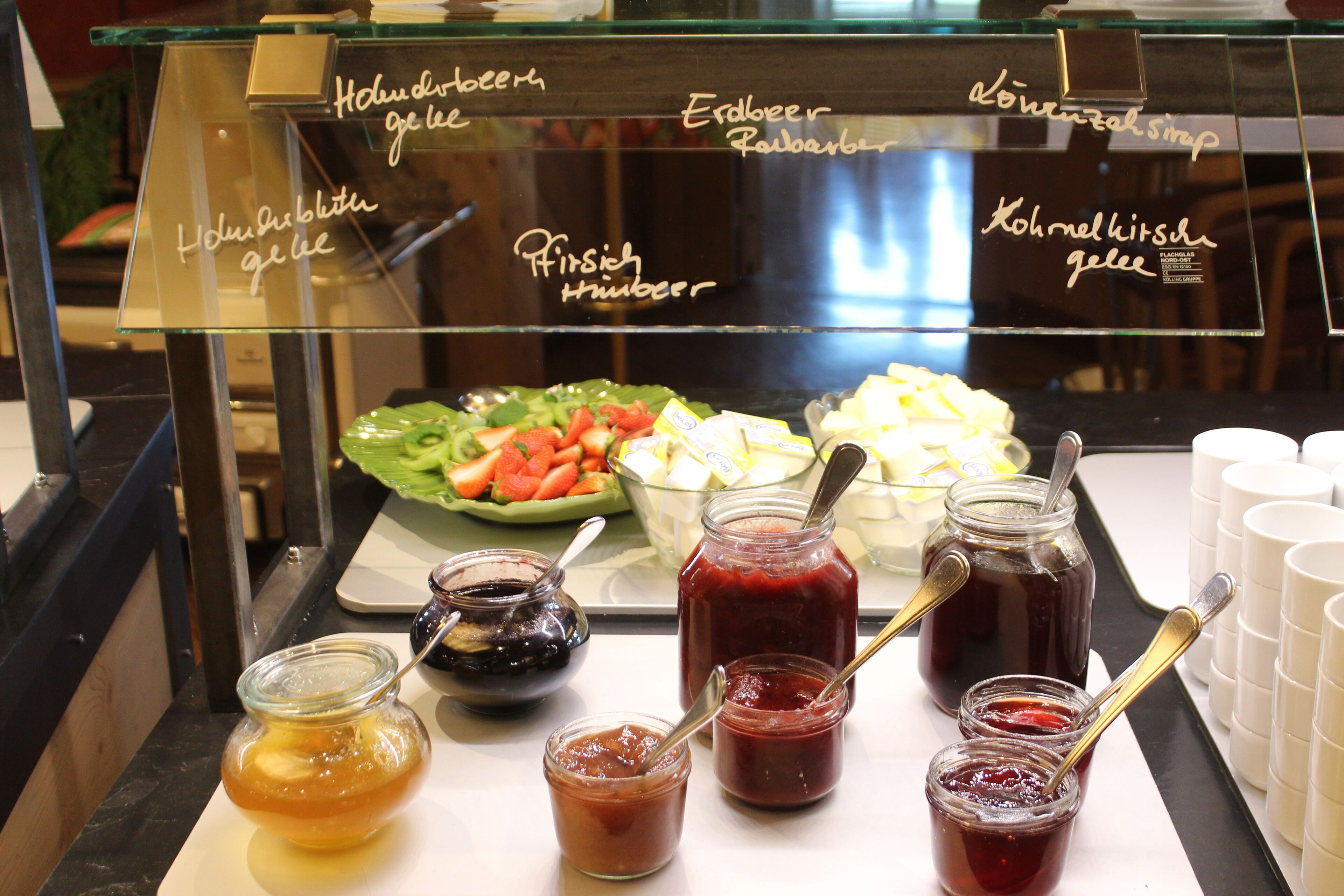 En madpræsentation med forskellige marmelader og en salat.