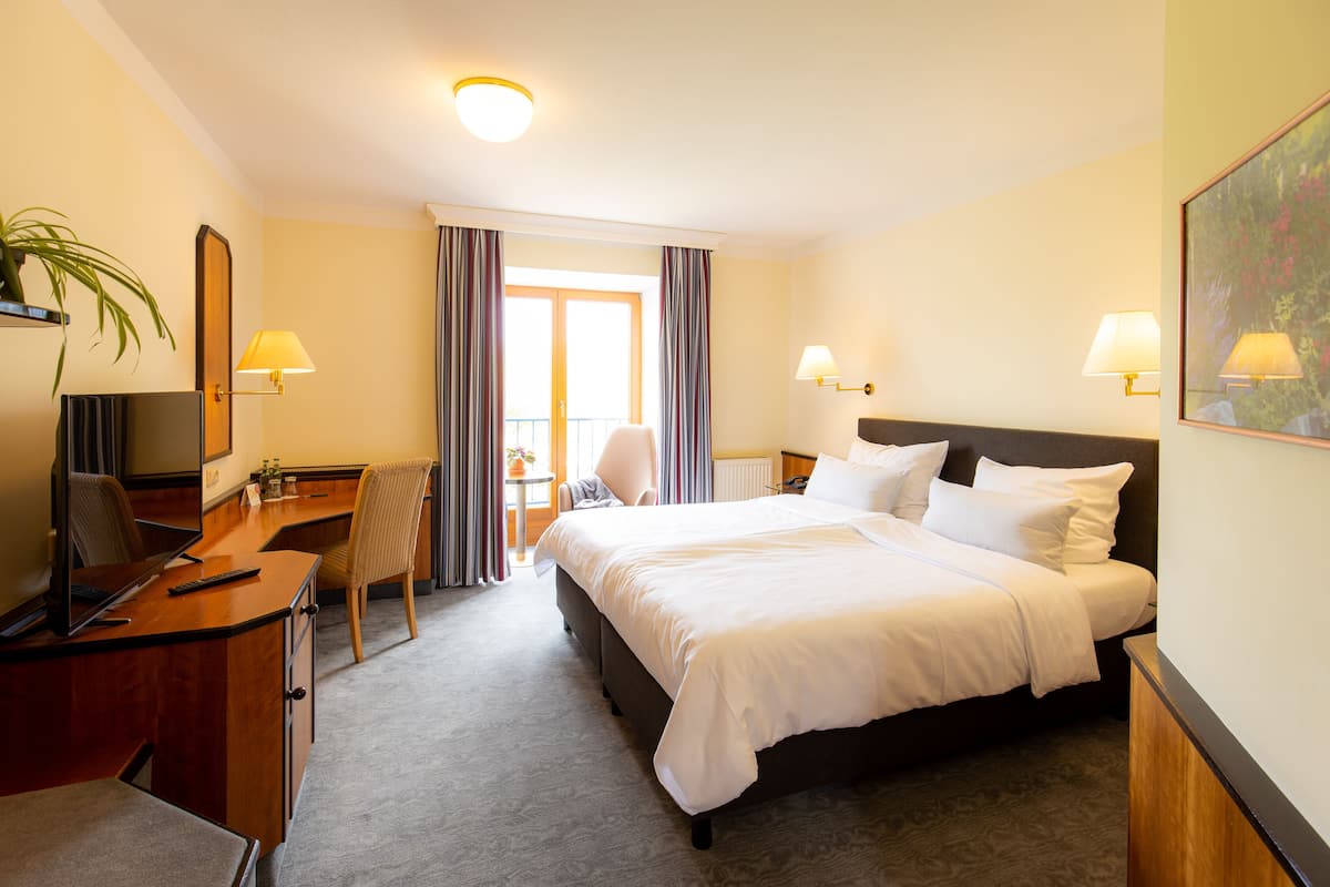 A hotel room with a bed, desk, chair, and two lamps.