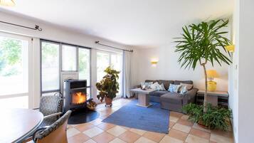 A living room with a fireplace, a sofa, a dining table, and potted plants.