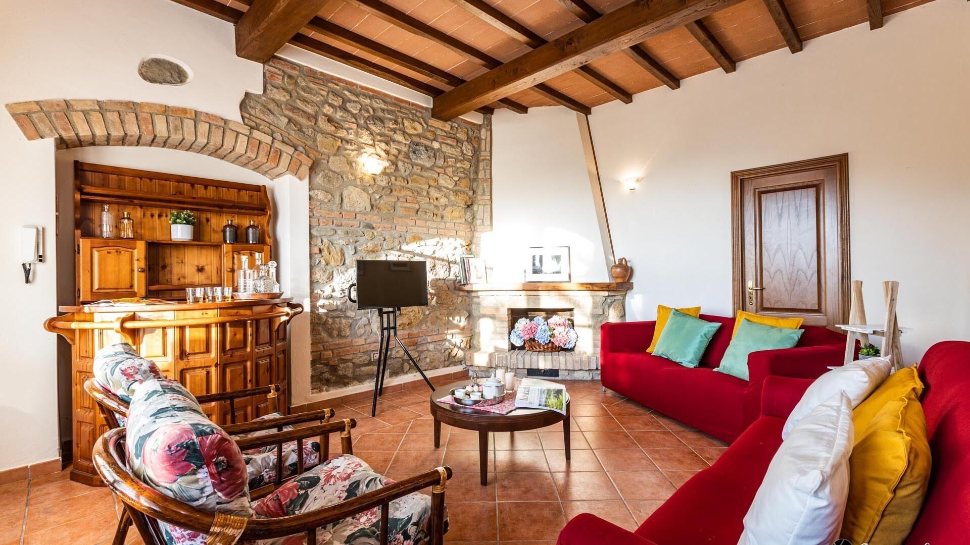 A cozy living room with a stone fireplace, wooden furniture, and a red sofa.