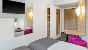 Een moderne hotelkamer met een bed, een aan de muur bevestigde televisie, een houten kast en een klein bureau met stoel.