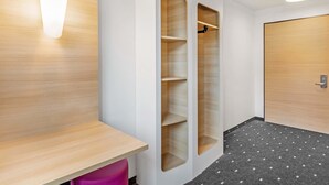 Een moderne badkamer met een houten wastafelmeubel, een douchegedeelte en een deur met een handgreep.
