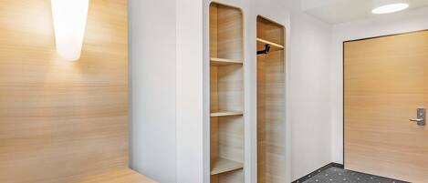 A modern bathroom with a wooden vanity, a shower area, and a door with a handle.