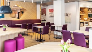 Een modern restaurantinterieur met houten accenten, paarse zittingen en moderne verlichtingsarmaturen.