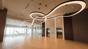 A spacious lobby with a modern light fixture, elevators, and a marble floor. - Marriott Fort Lauderdale Airport (Dania Beach)