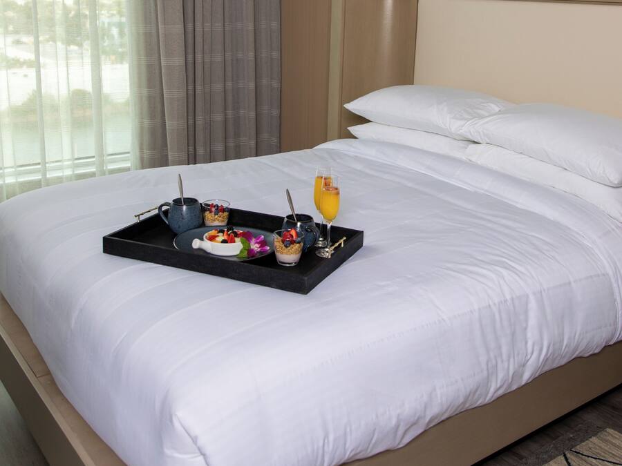 Quarto de hotel com uma cama, um serviço de mesa com itens de café da manhã e vista para o exterior pela janela.