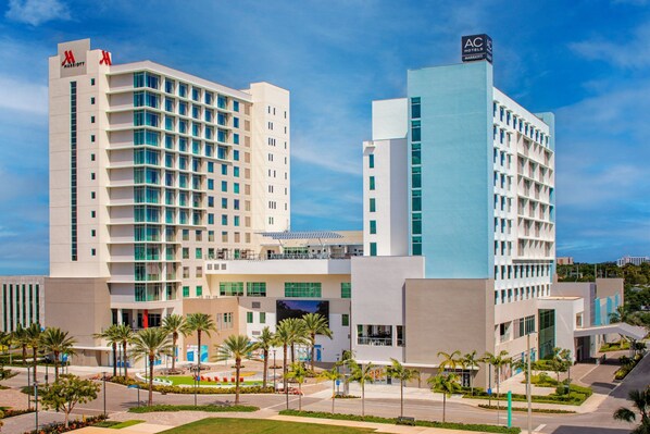 A modern hotel with a prominent AC logo, multiple floors, and a central courtyard with palm trees. - Marriott Fort Lauderdale Airport (Dania Beach)