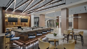 A modern bar area with a central island, seating, and a staircase. - Marriott Fort Lauderdale Airport (Dania Beach)