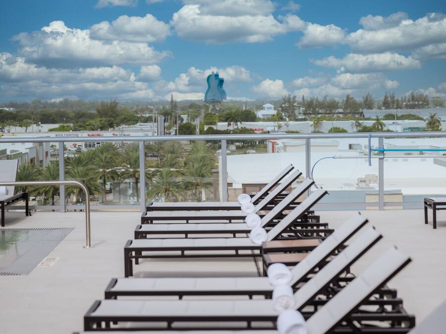 A rooftop lounge area with sun loungers and a view of the cityscape.