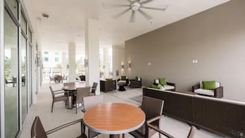A modern outdoor lounge area with wicker furniture, a round wooden table, and a ceiling fan.