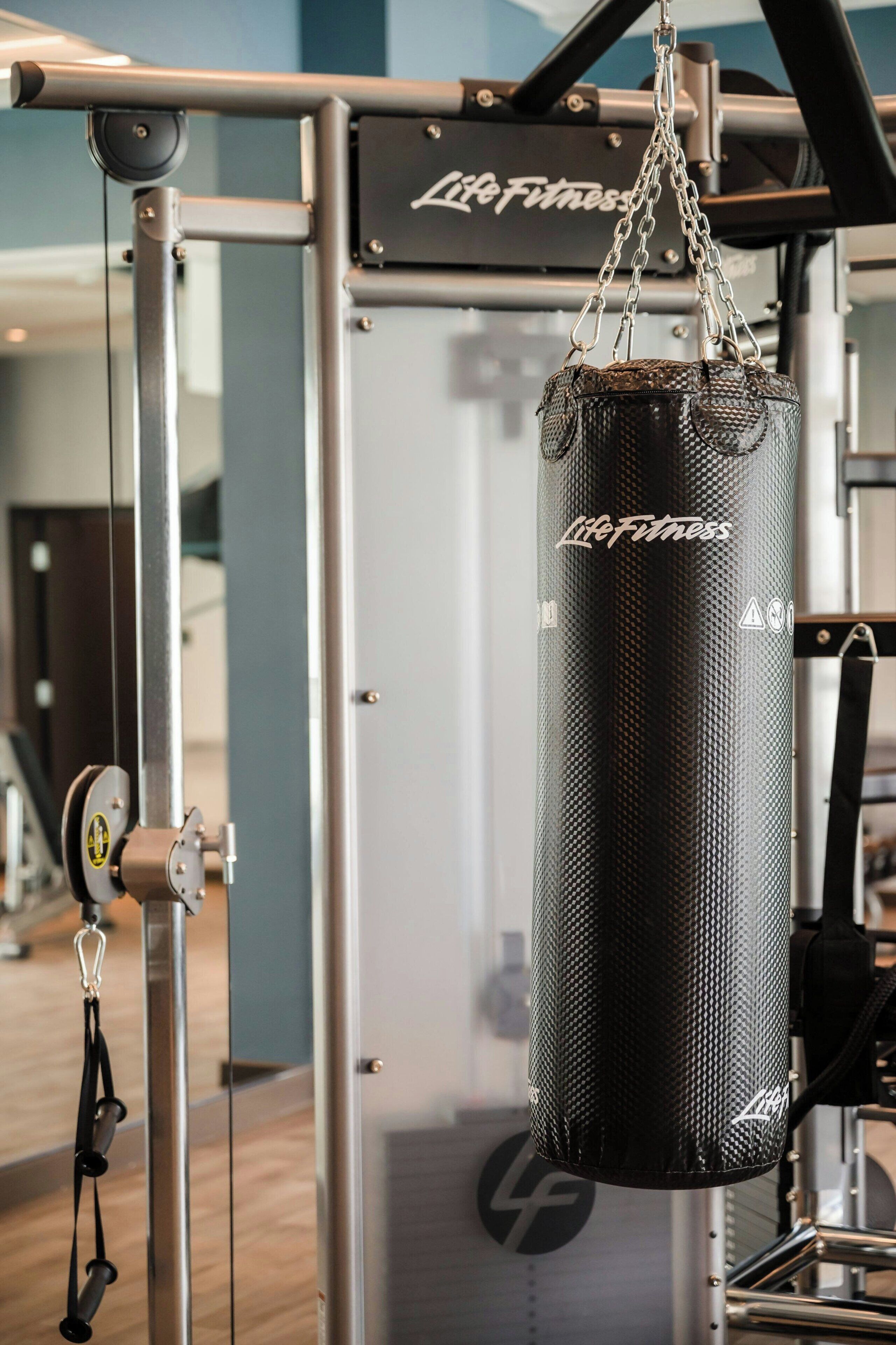 A gym with a punching bag hanging from a metal frame, a weight stack, and a mirror.
