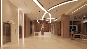 A spacious lobby with a modern reception desk, elevators, and a dining area. - Marriott Fort Lauderdale Airport (Dania Beach)