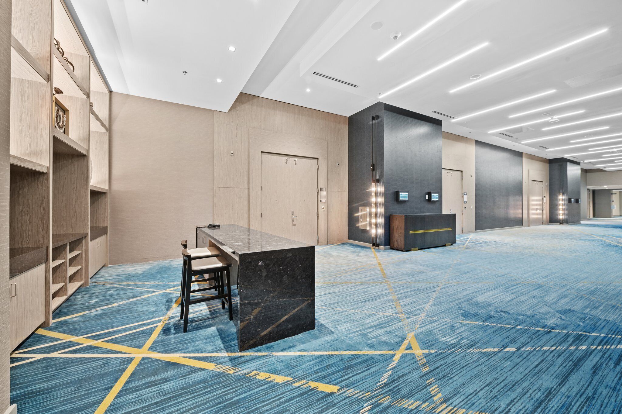 A spacious hotel lobby with a long reception desk, seating area, and lockers.