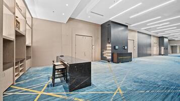 A spacious hotel lobby with a long reception desk, seating area, and lockers.
