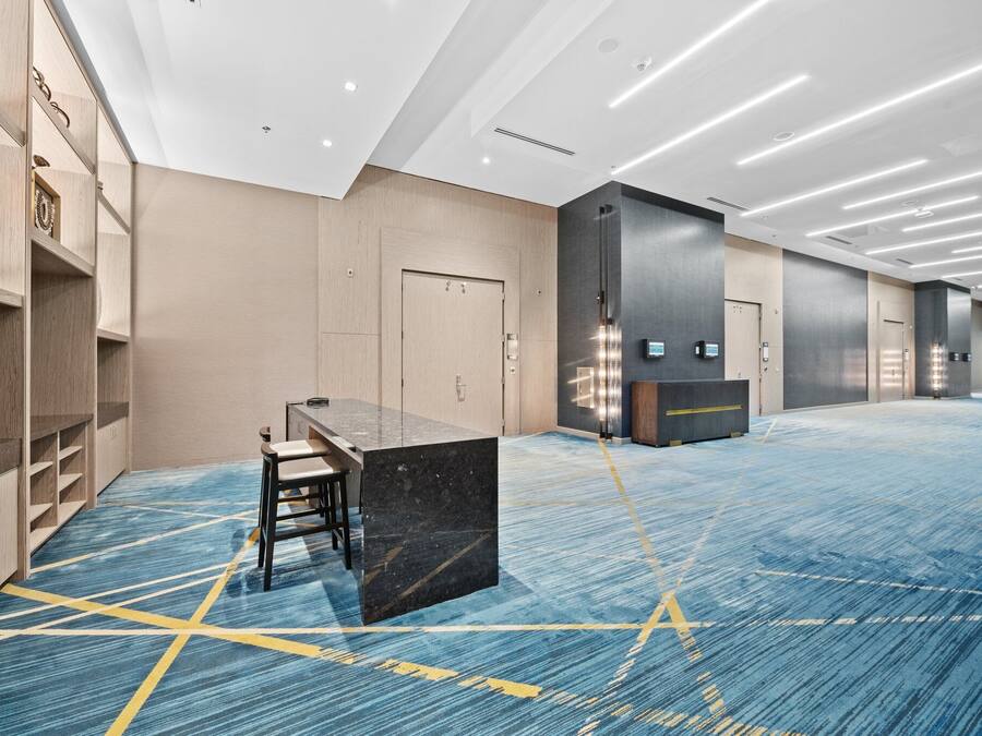 A spacious hotel lobby with a long reception desk, seating area, and lockers.
