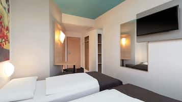 Una habitación de hotel con dos camas, un televisor montado en la pared y un cuadro.