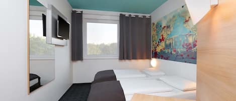 A hotel room with a bed, a desk, a TV, and a window with curtains.