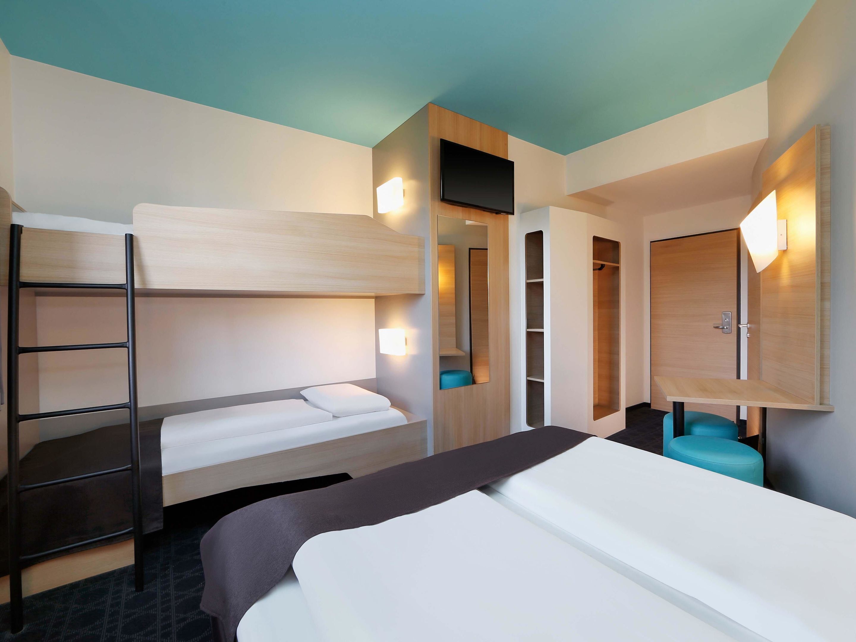 A bunk bed room with a ladder, a desk, and a chair.