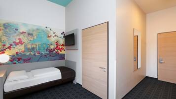 Ett modernt hotellrum med ett stort konstverk på väggen, en säng, ett sängbord och en spegel.